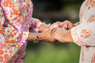 due figure femminili si tengono per mano