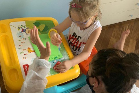 Little girl writing on a small whiteboard along with her teacher